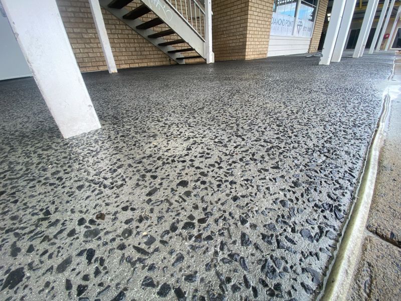 Two construction workers installing a red drainage pipe on a job site near a building.