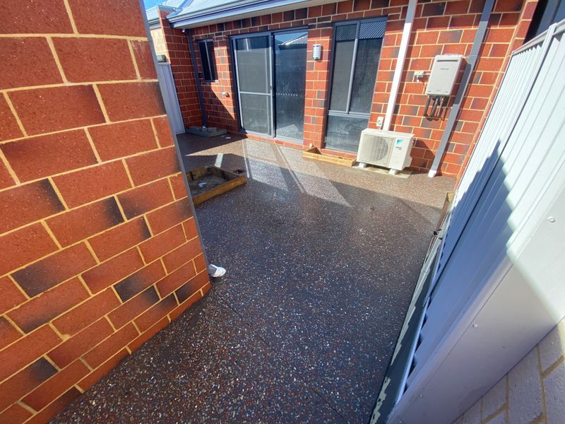 Two construction workers installing a red drainage pipe on a job site near a building.