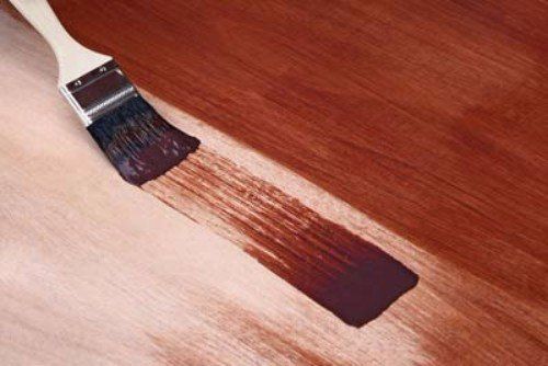 un pennello che tinge una superficie in legno di marrone
