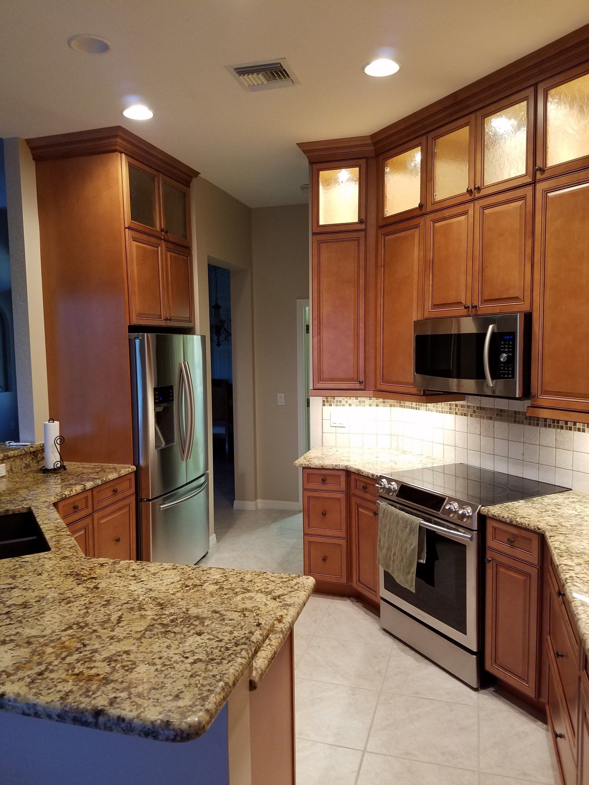 Kitchen with wooden cabinets, stainless steel appliances, granite countertops, and tile backsplash.