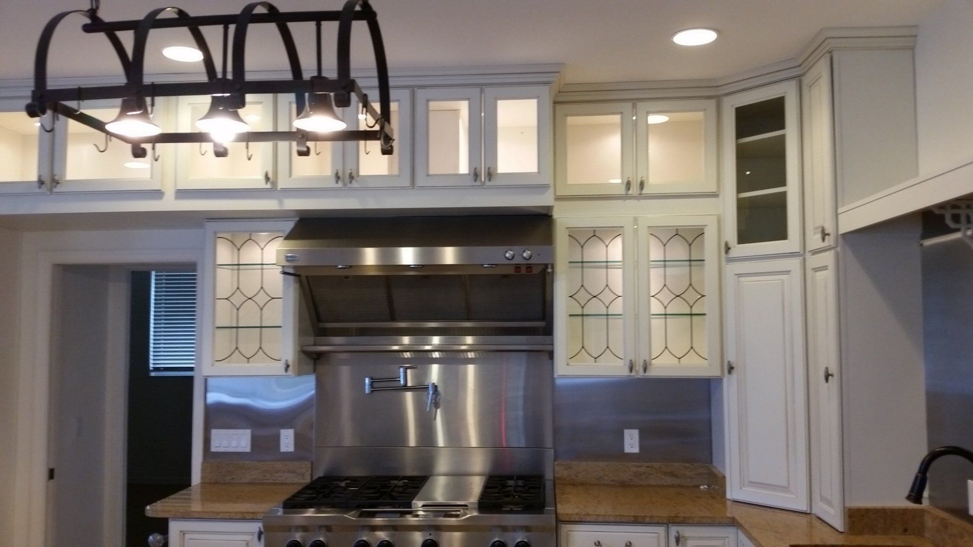 Kitchen with white cabinets, stainless steel appliances, and light fixtures.