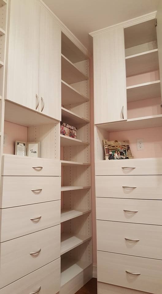 Custom walk-in closet with white cabinets, drawers, and shelves.