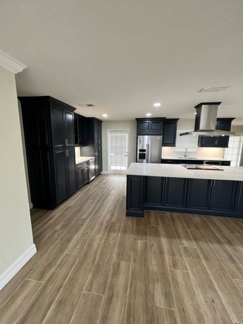 Spacious kitchen with dark blue cabinets, white countertops, and light wood-look flooring.