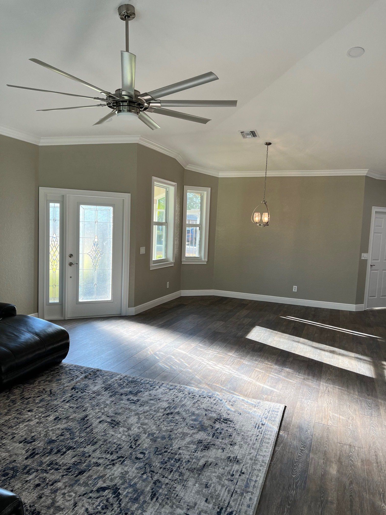 Living room with dark wood floors, neutral walls, ceiling fan, and sunlight.