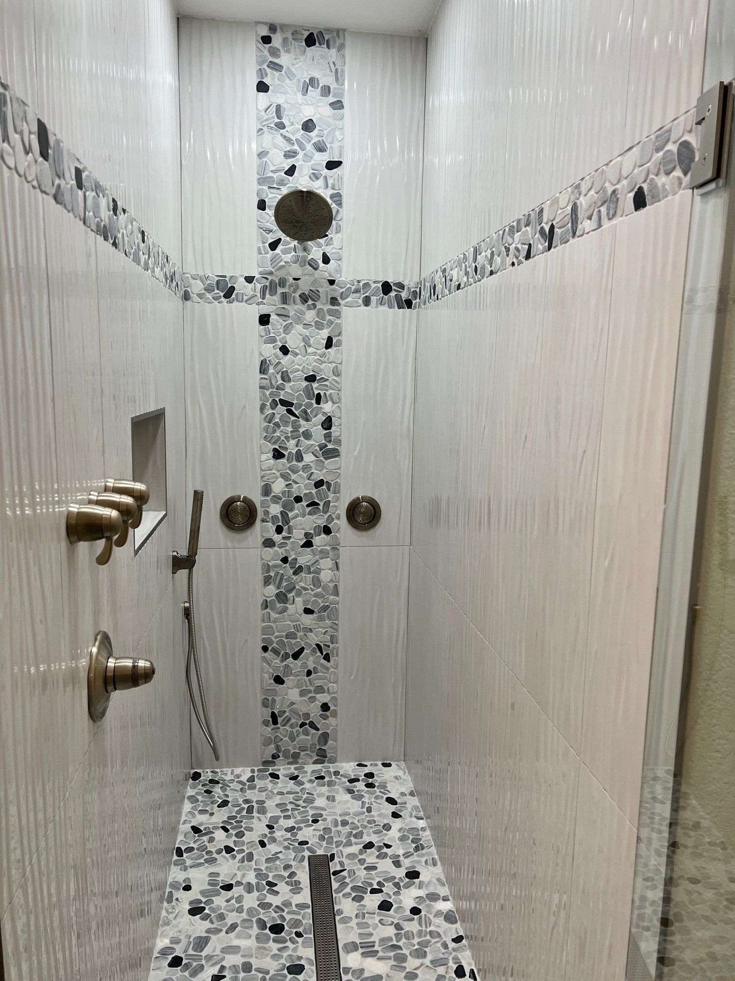 White tiled shower with mosaic tile accents, bronze fixtures.