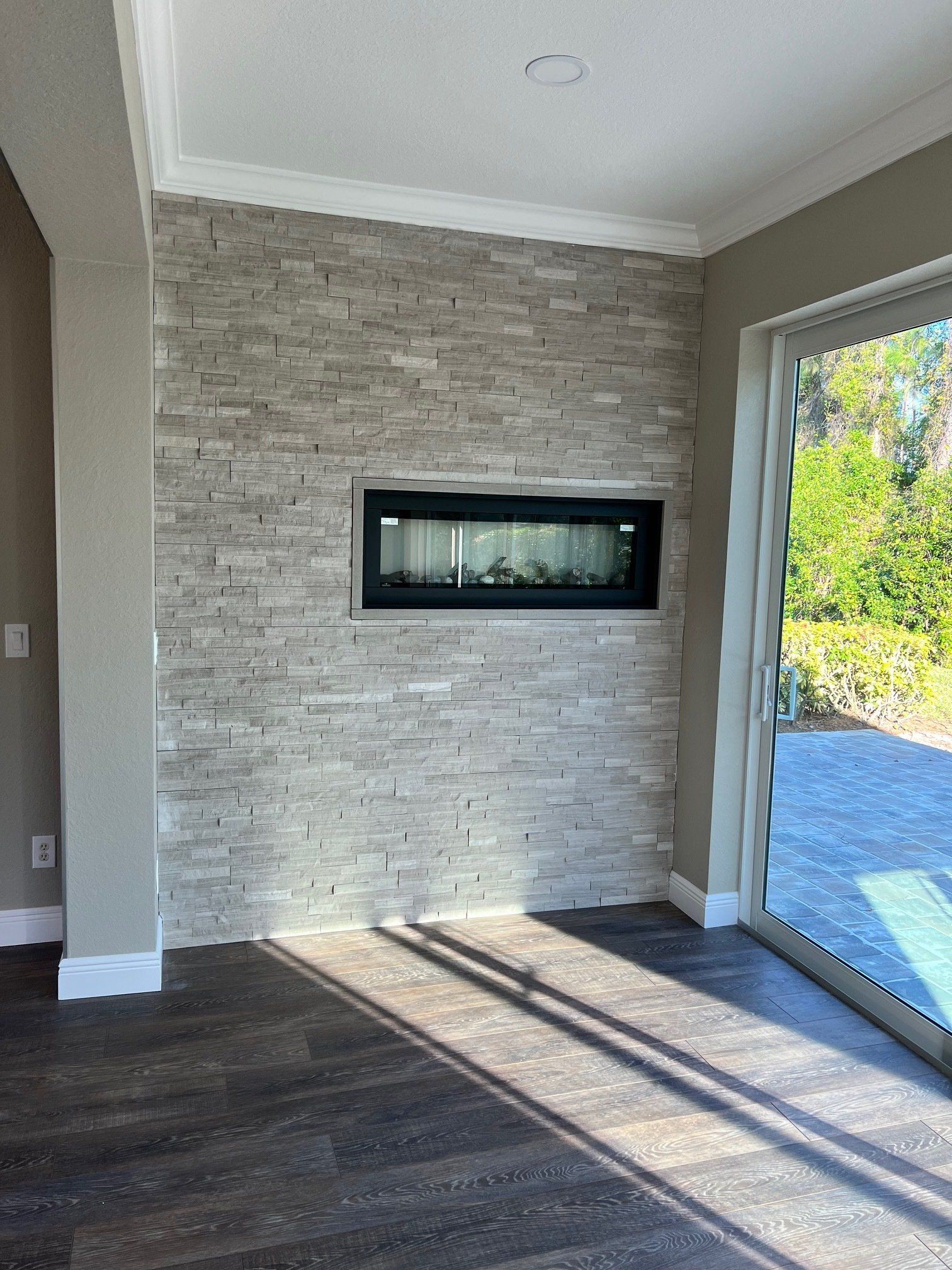 Gray brick wall with a fireplace, next to a sliding glass door.
