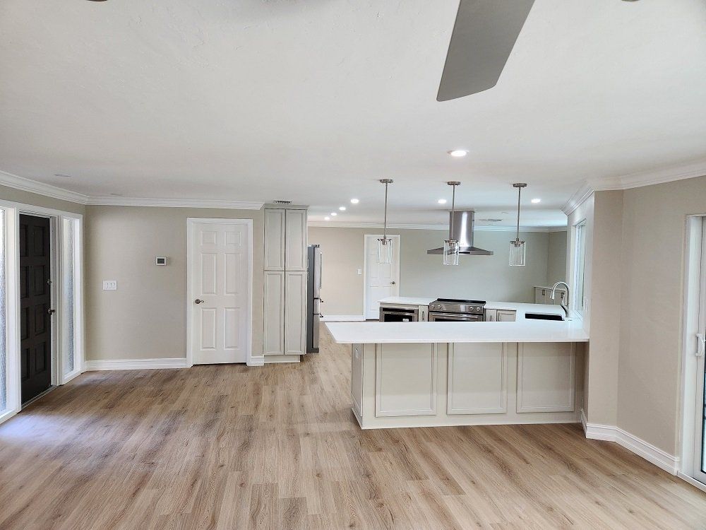 Open-concept kitchen with white cabinetry, wood flooring, and a breakfast bar. Sliding doors on either side of the room.