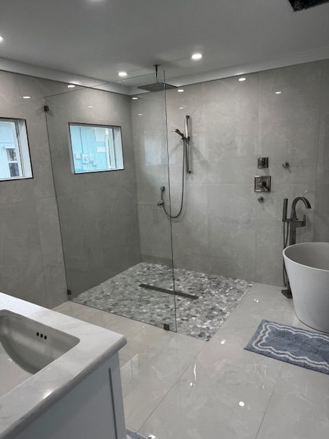 Small bathroom with a toilet, vanity, and wooden floor. Light blue walls, white trim, and a decorative mirror.