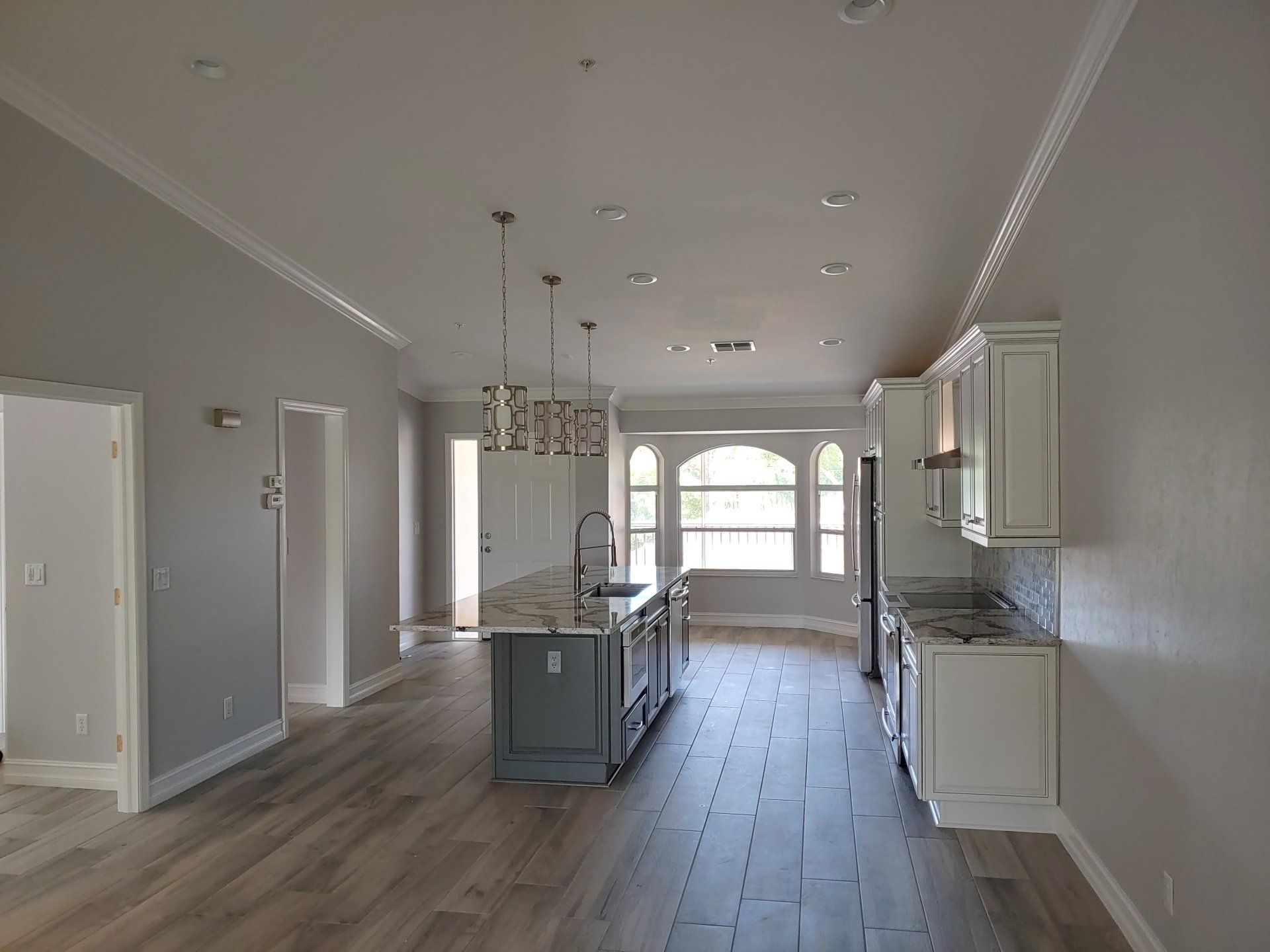 Spacious, modern kitchen with gray walls, a blue island, and white cabinets.