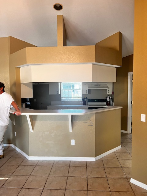 Kitchen with white cabinets, light blue walls, and a counter looking out to a patio.