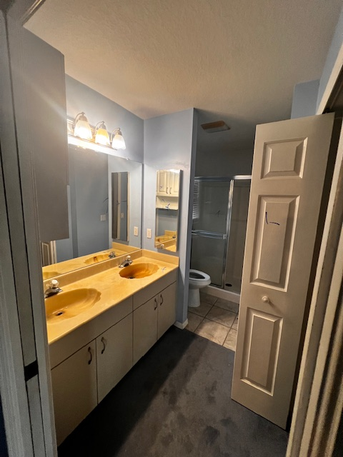 Bathroom with dark wood floor, orange walls, toilet, sink, and glass shower door.