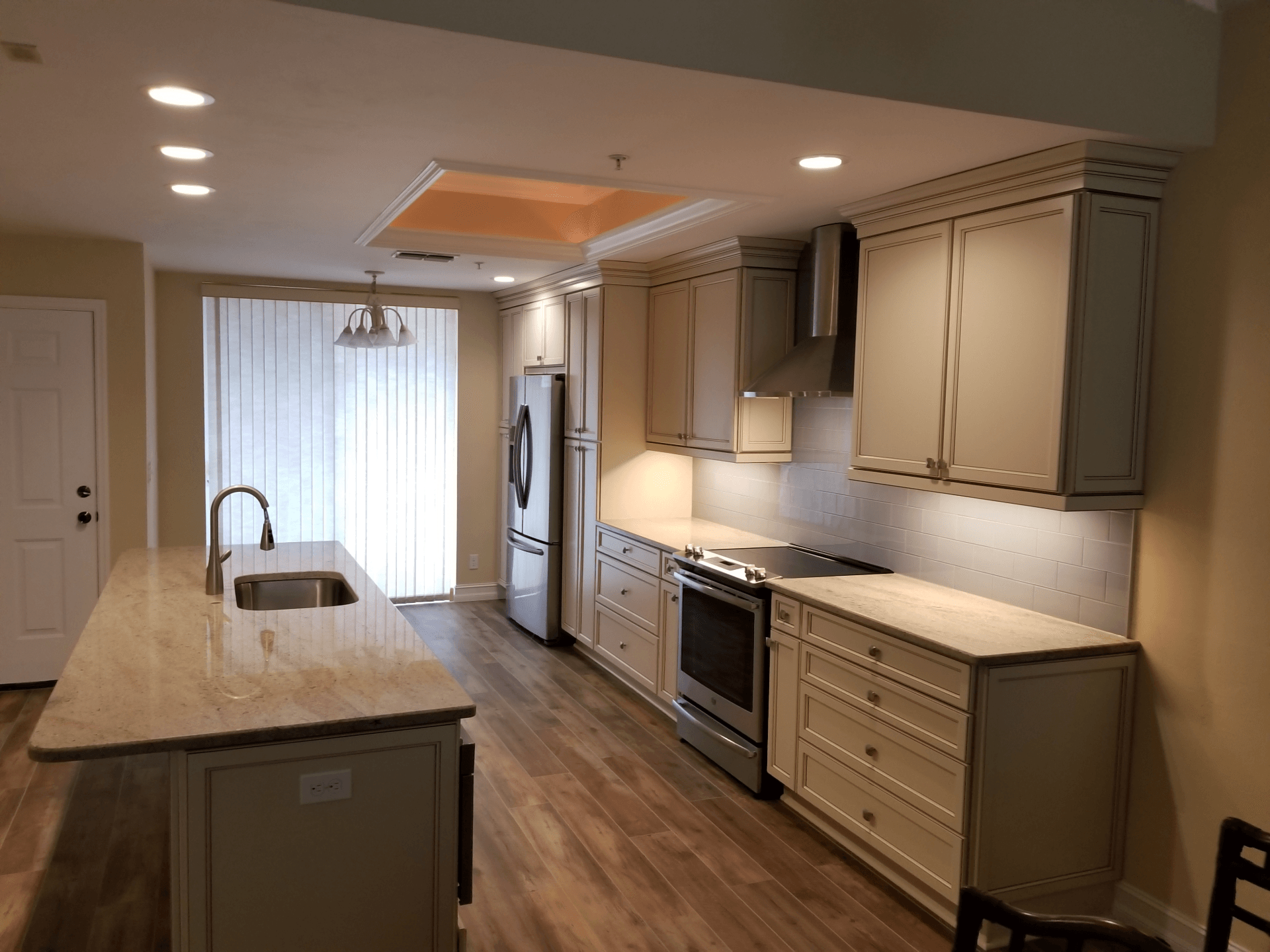 Modern kitchen with beige cabinets, stainless steel appliances, and island.