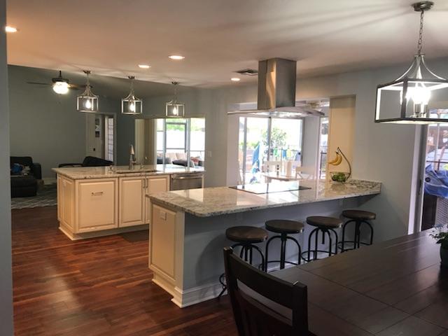 Open-concept kitchen with two islands, granite countertops, bar stools, and a dining table.