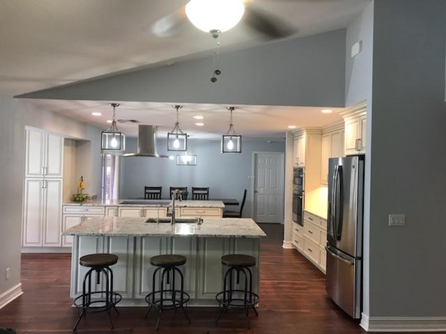 Modern kitchen with white cabinets, granite island with stools, and stainless steel appliances.