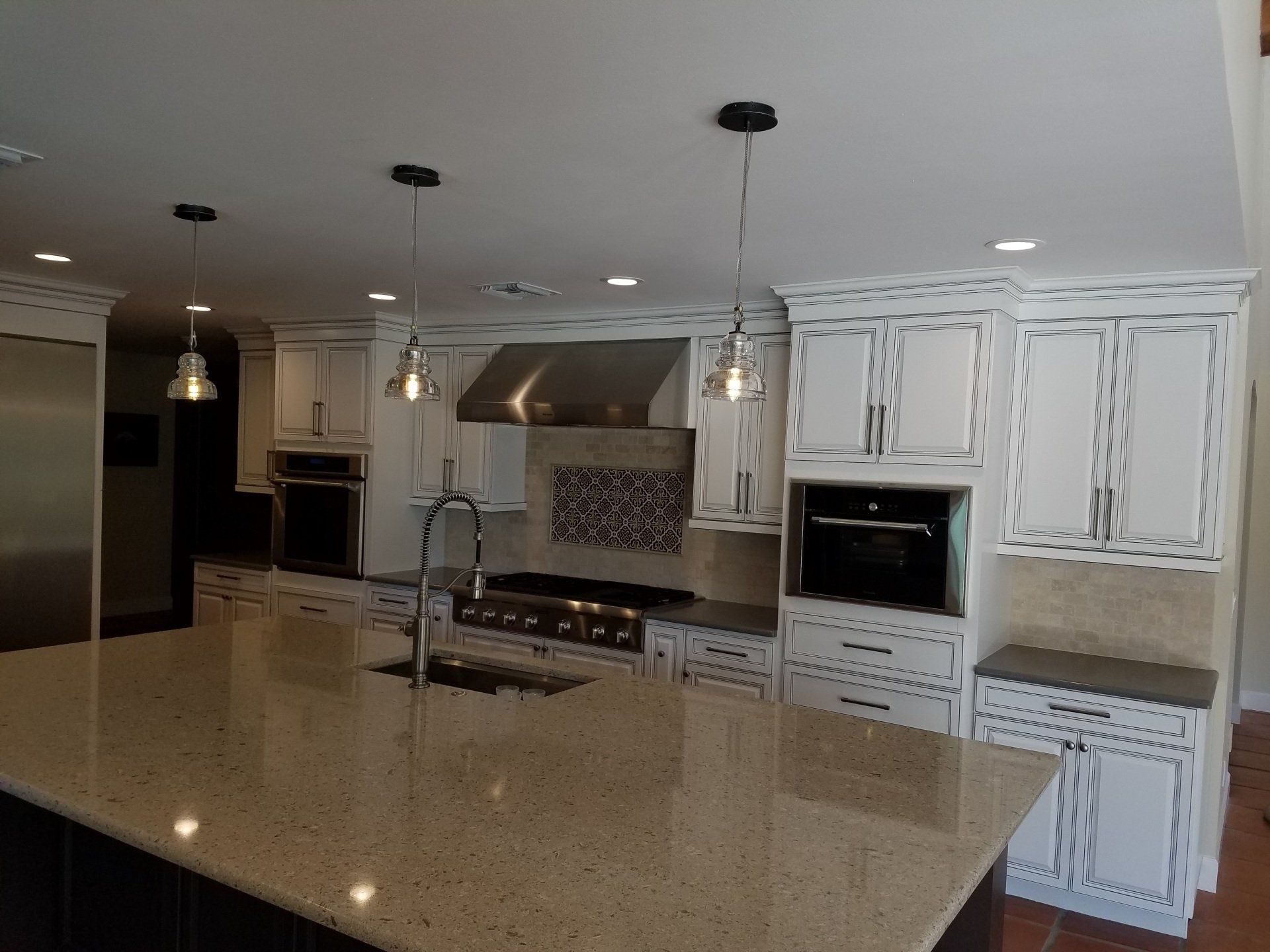 Modern kitchen with white cabinets, large island, granite countertops, and stainless steel appliances.