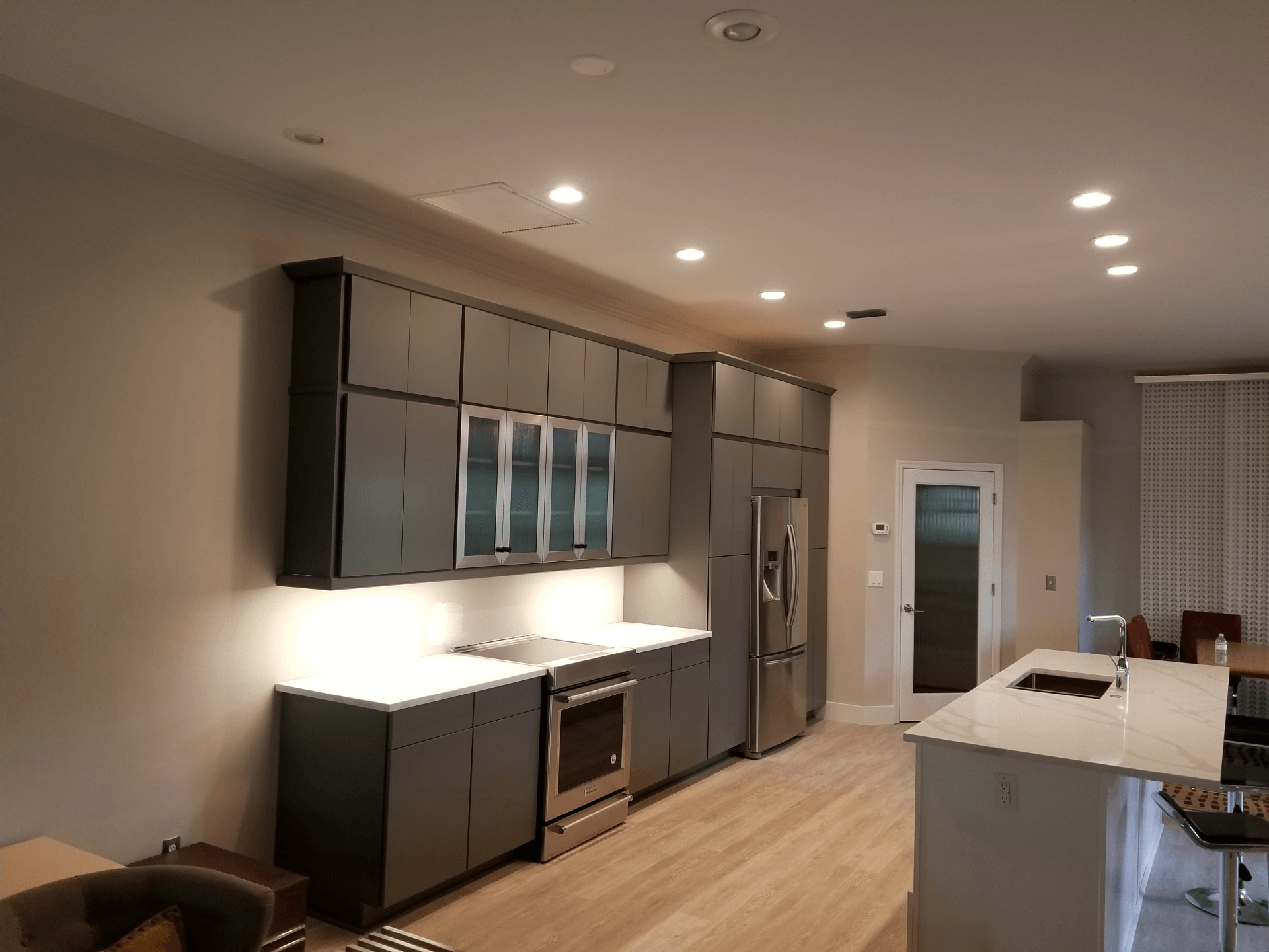 Modern kitchen with gray cabinets, stainless steel appliances, and white countertops.