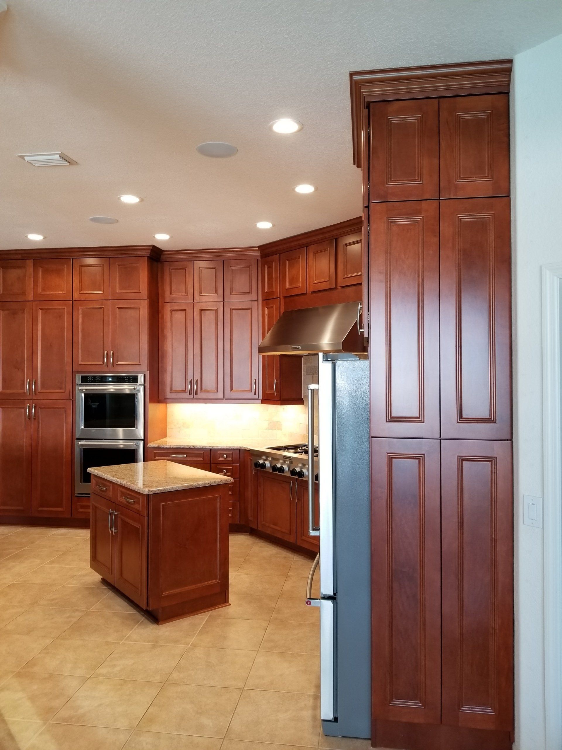 Kitchen with dark wood cabinets, island, and stainless steel appliances.
