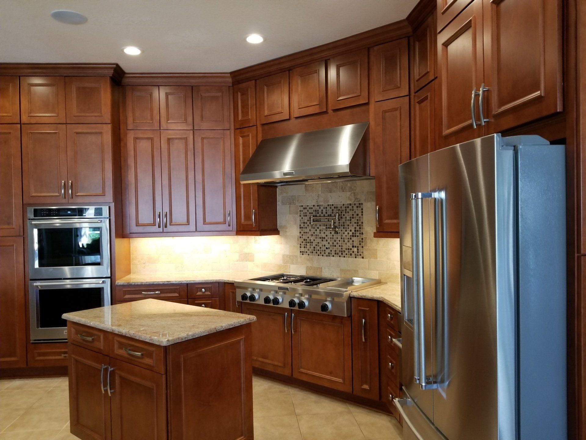 A kitchen with dark wood cabinets, stainless steel appliances, and a granite island.