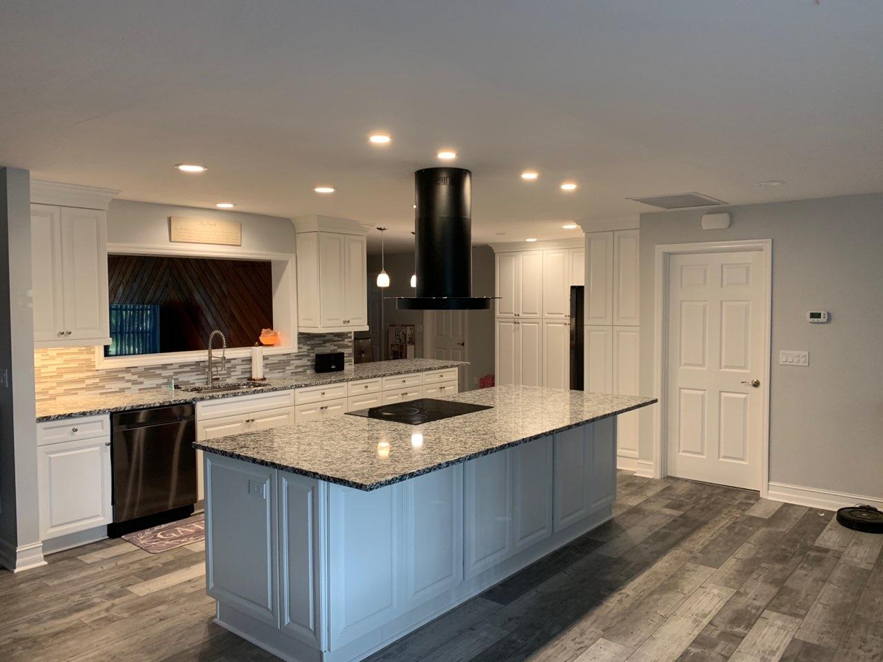 Modern kitchen remodel with white cabinets, granite countertops, and a black range hood.