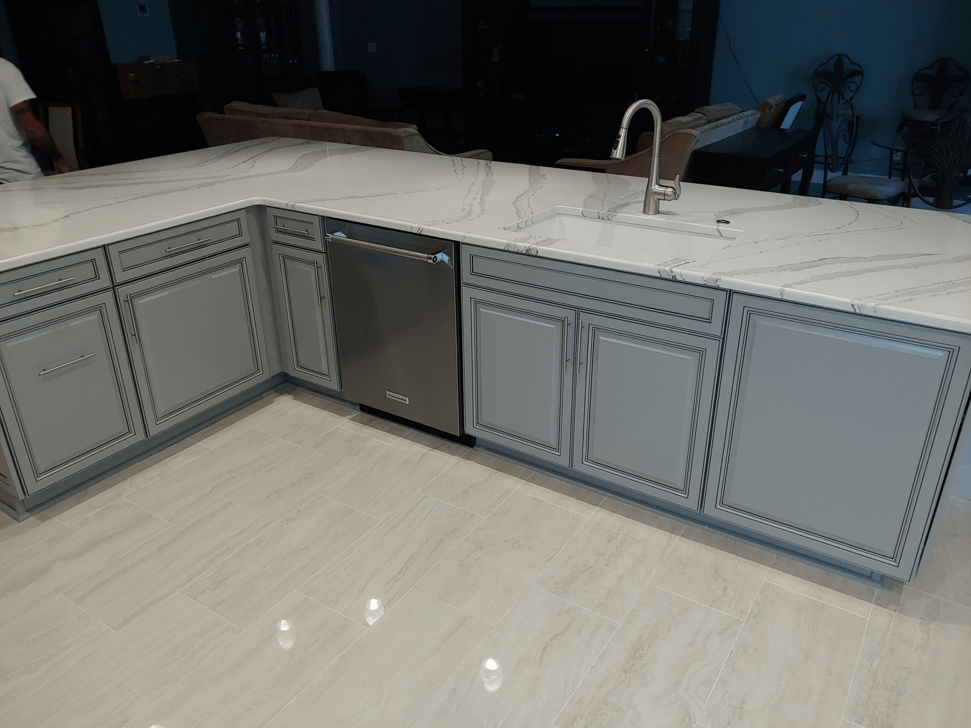 Light blue kitchen cabinets with a dishwasher, topped with white marble countertops.