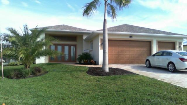 A one-story house with a light-colored exterior, wooden garage doors, and a palm tree in front.