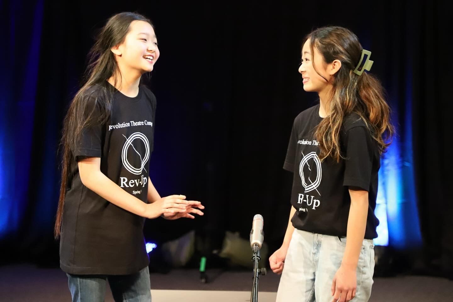 Two young girls are standing next to each other on a stage.