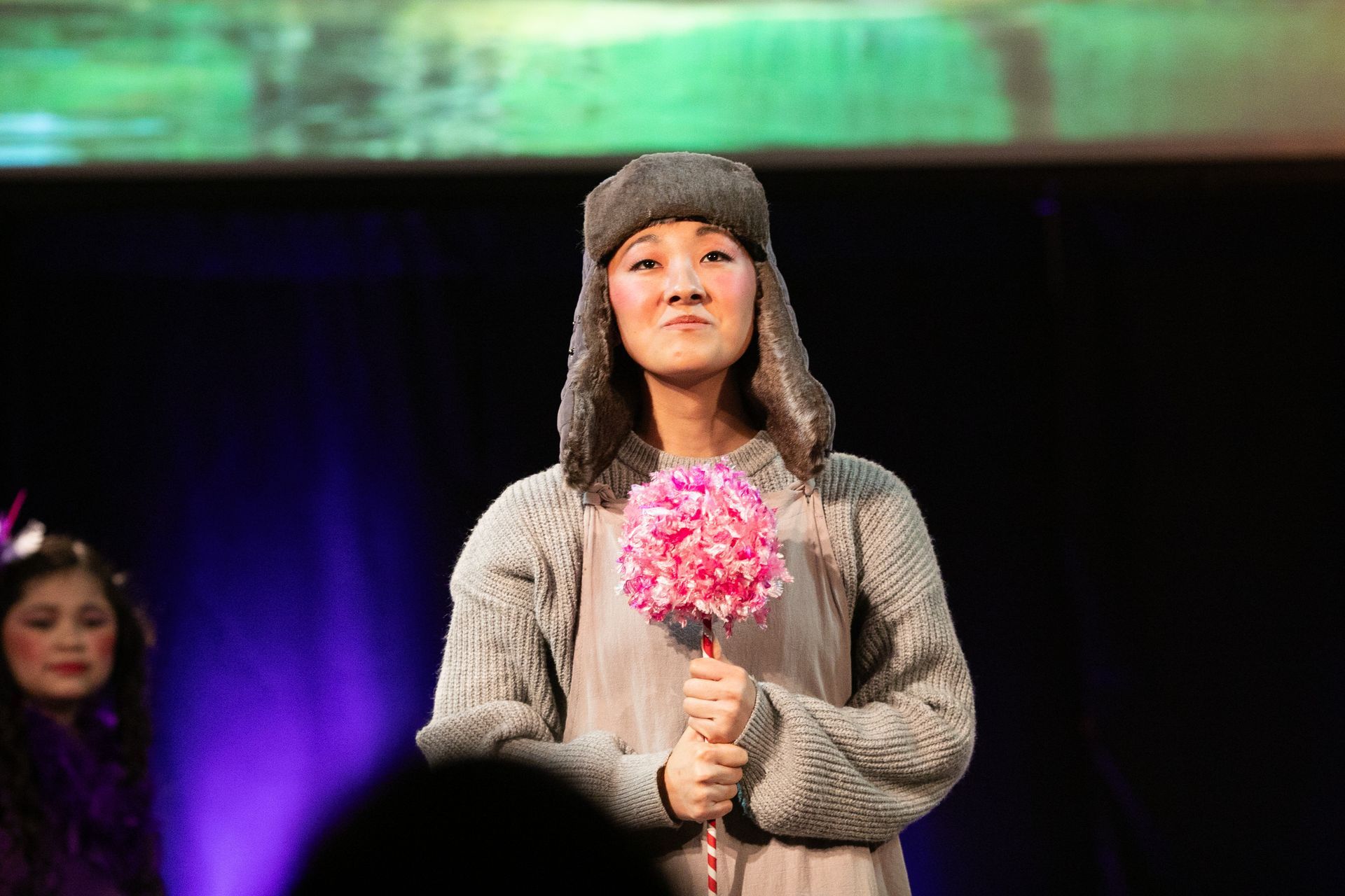 A woman is holding a bouquet of pink flowers on a stick.