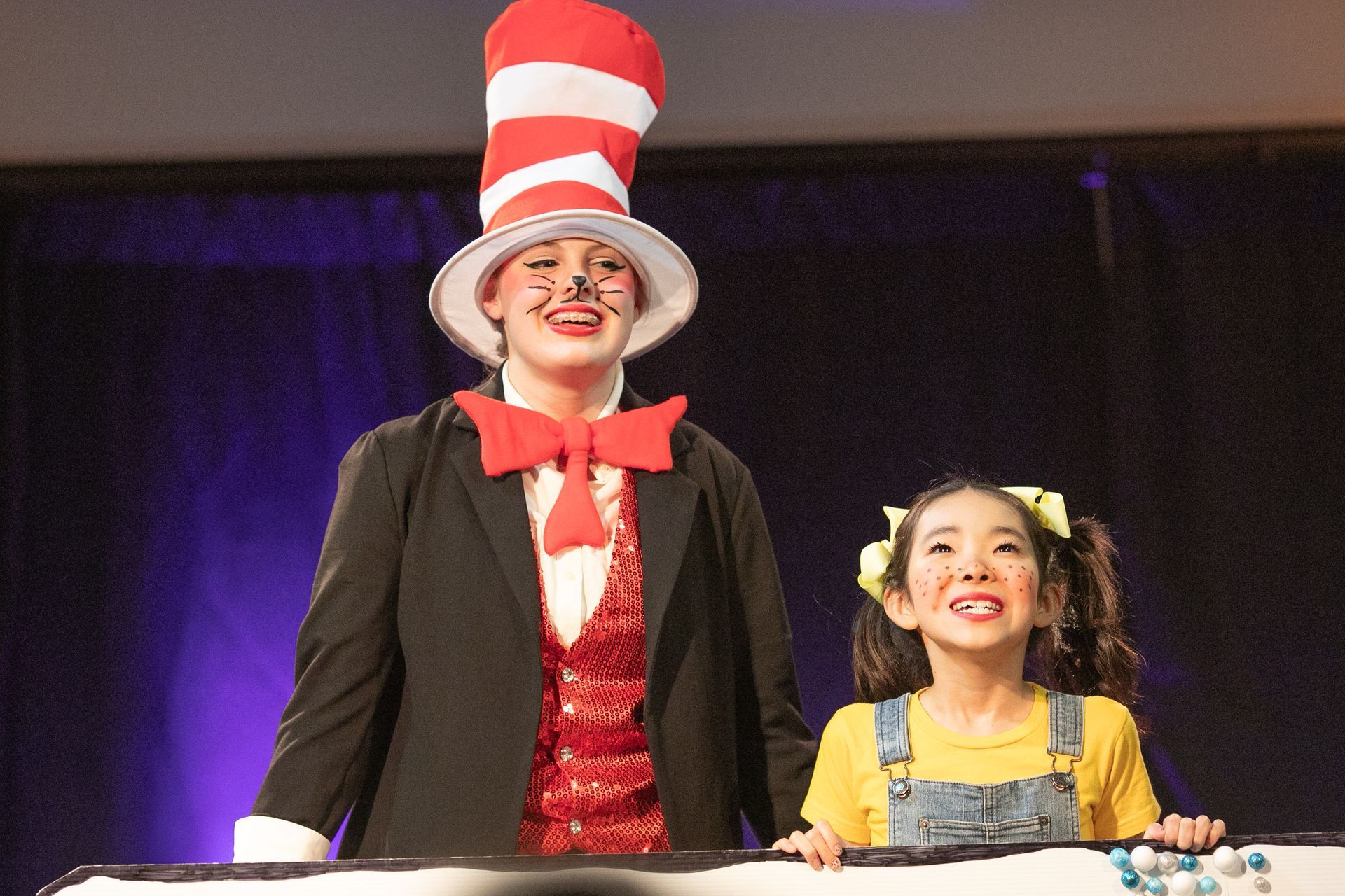 A woman in a cat in the hat costume is standing next to a little girl.