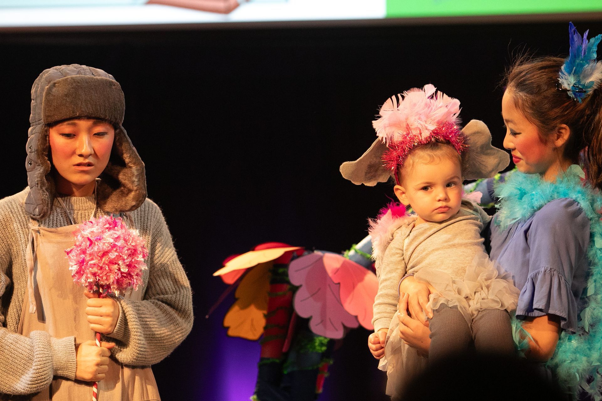 A woman holding a baby while another woman holds flowers