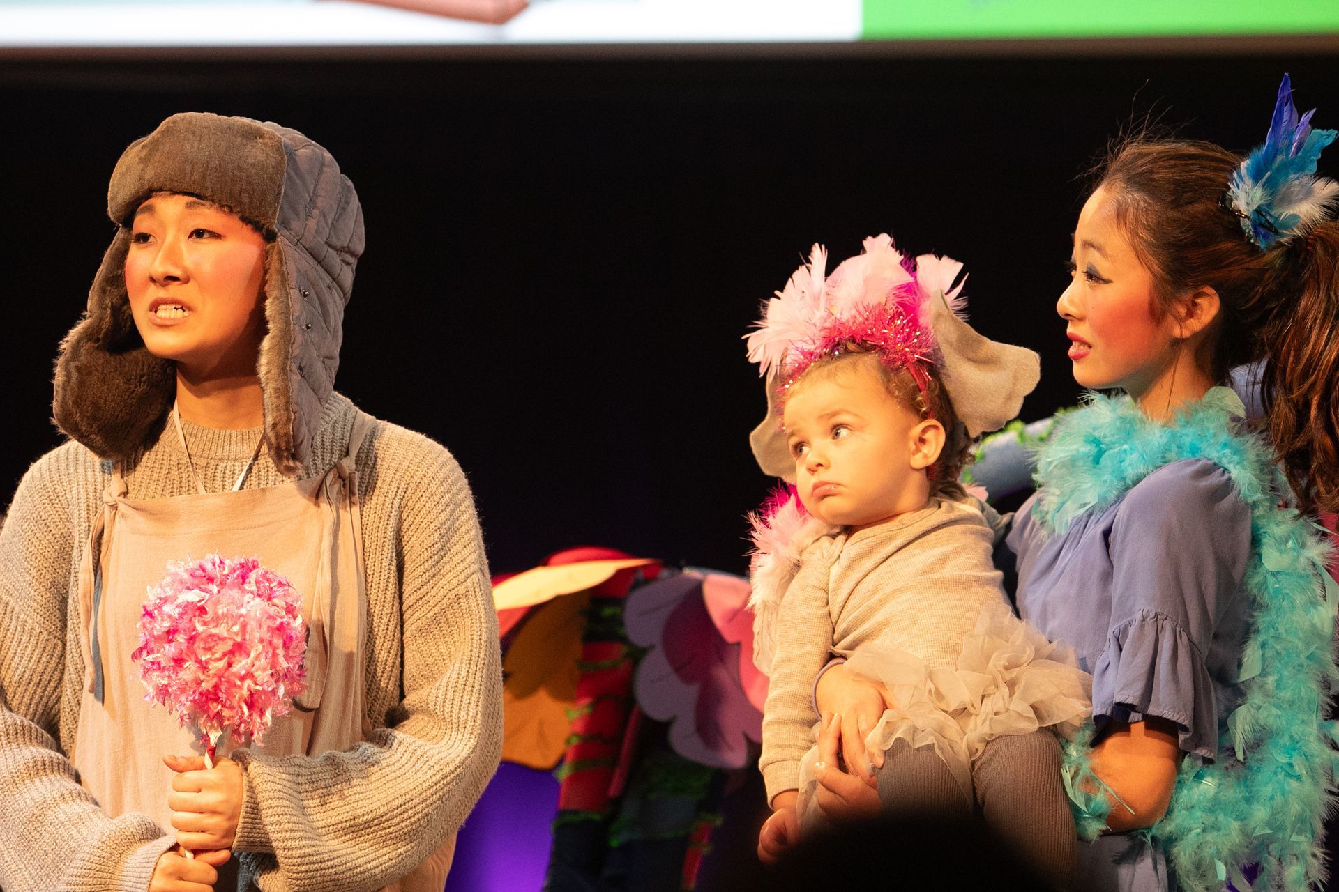 A woman is holding a baby in her arms on a stage