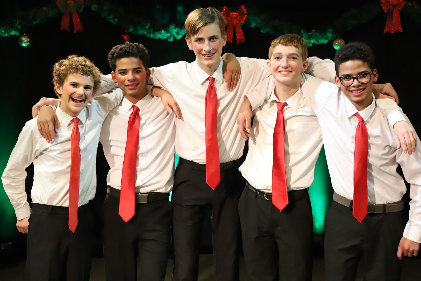 A group of young men wearing white shirts and red ties are posing for a picture.