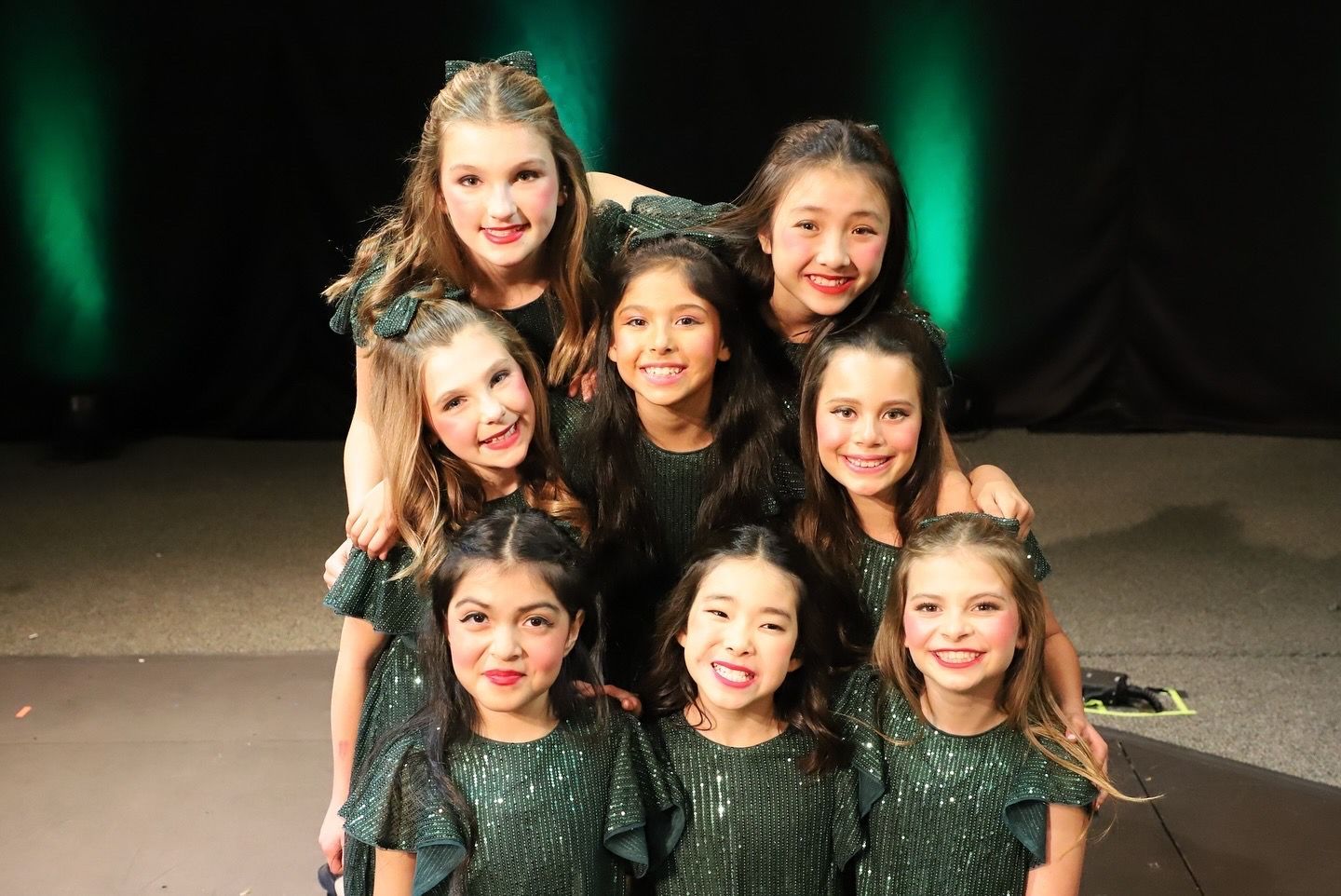 A group of young girls are posing for a picture on a stage.