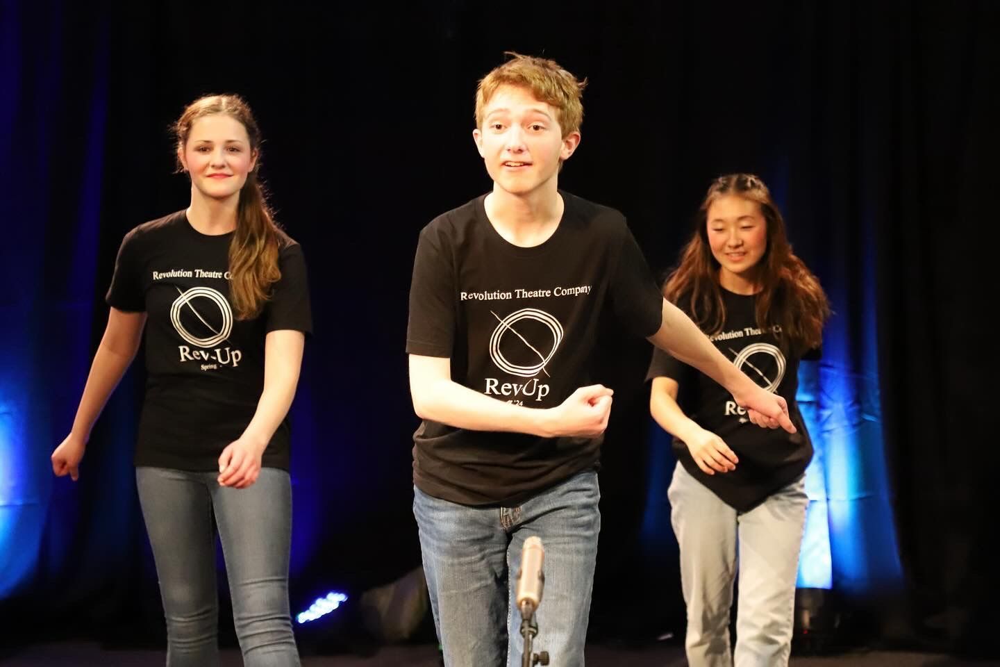 A boy and two girls are dancing on a stage.