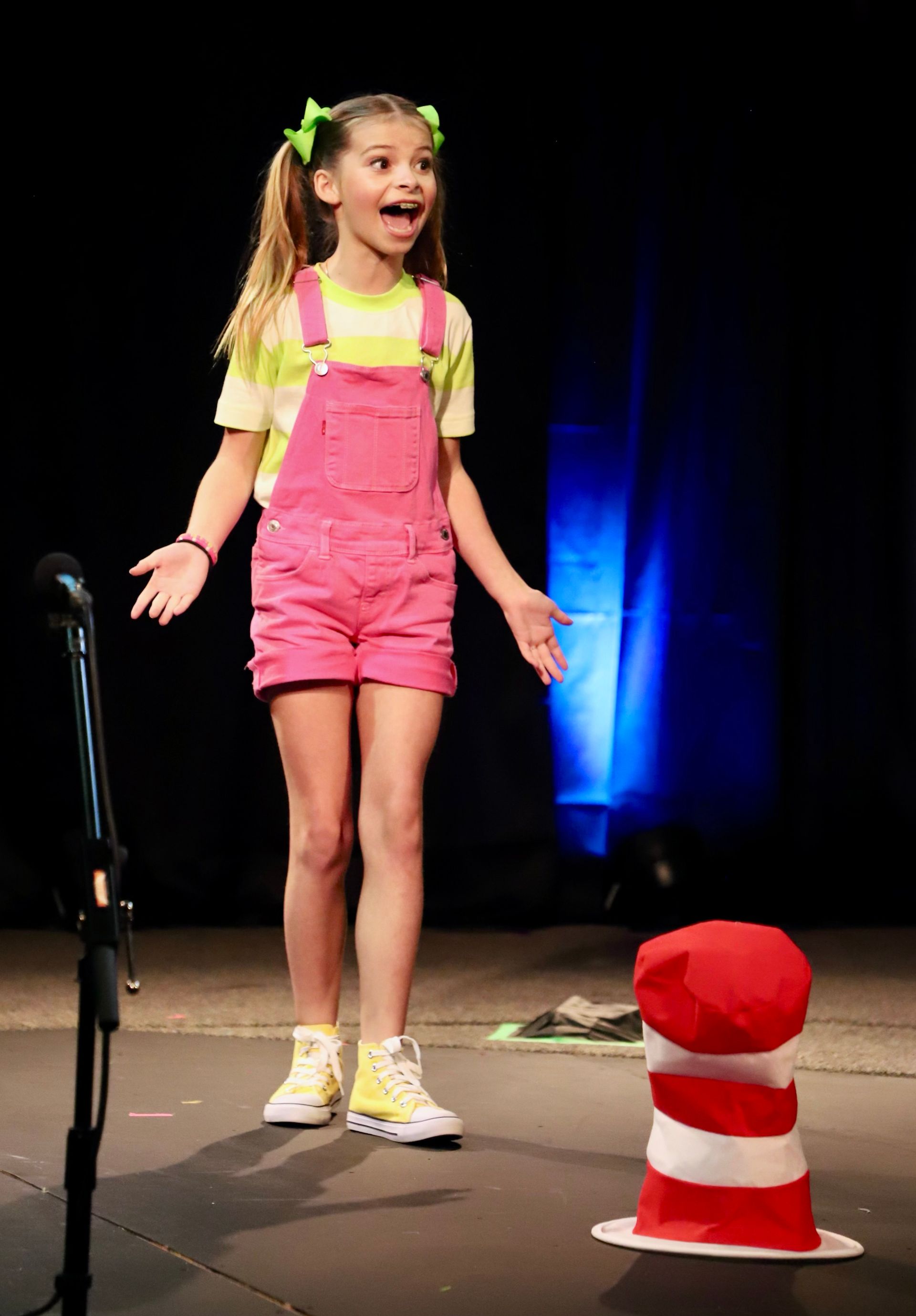 A girl on stage with her arms out as if she is raising them