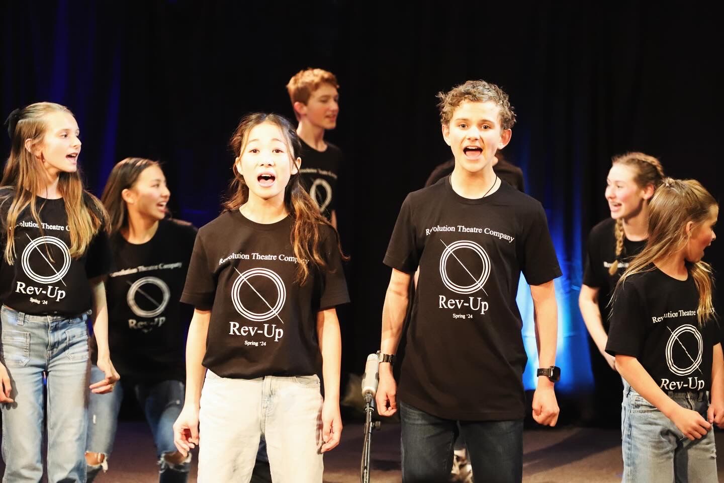 A group of young people are singing on a stage.