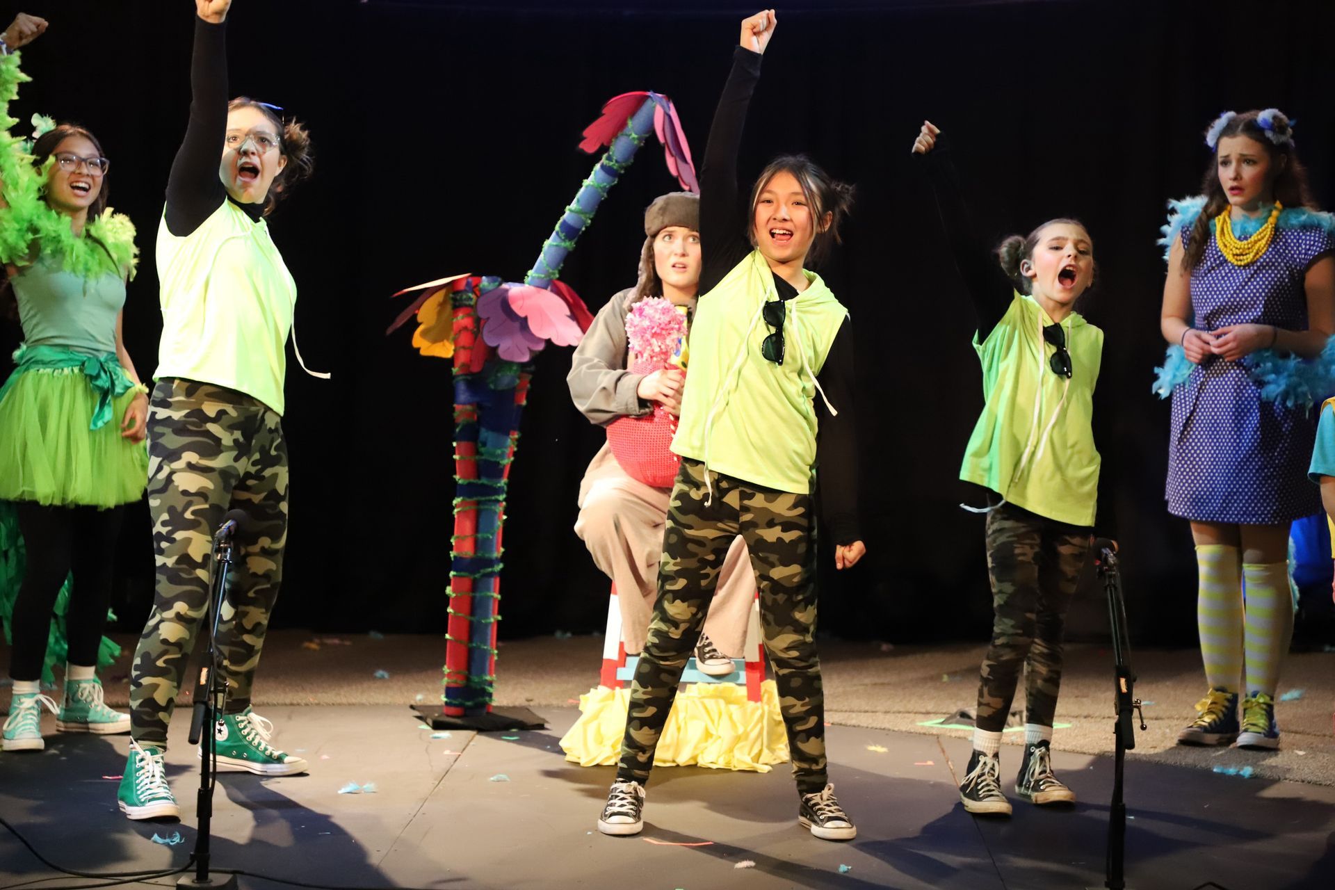 A group of children are singing into microphones on a stage.