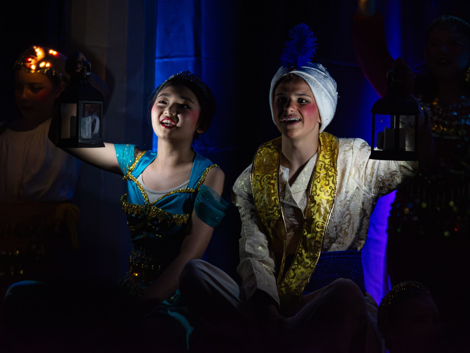 A man and a woman are sitting next to each other in a dark room holding lanterns.