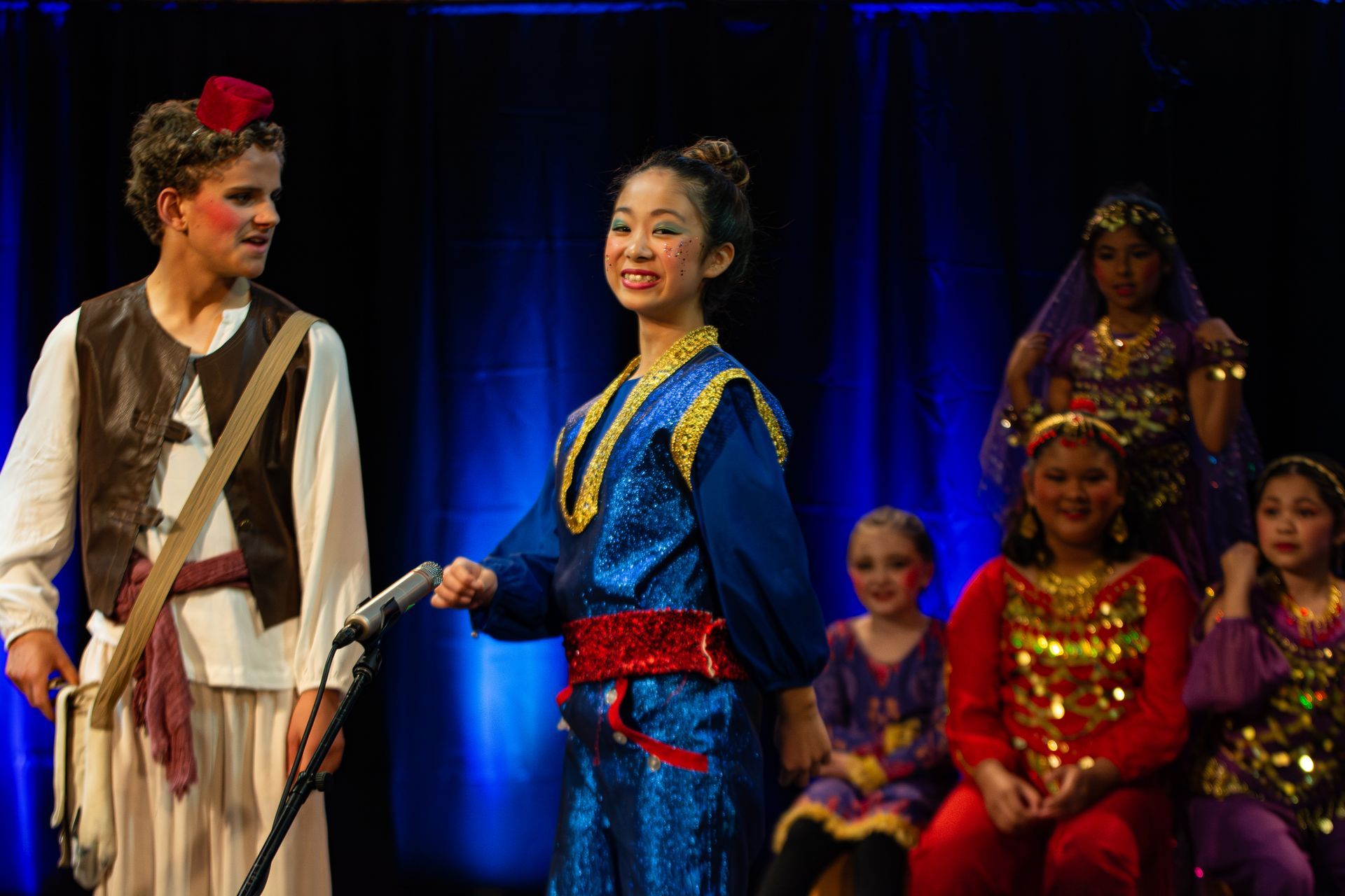 A boy and a girl are standing next to each other on a stage holding a microphone.