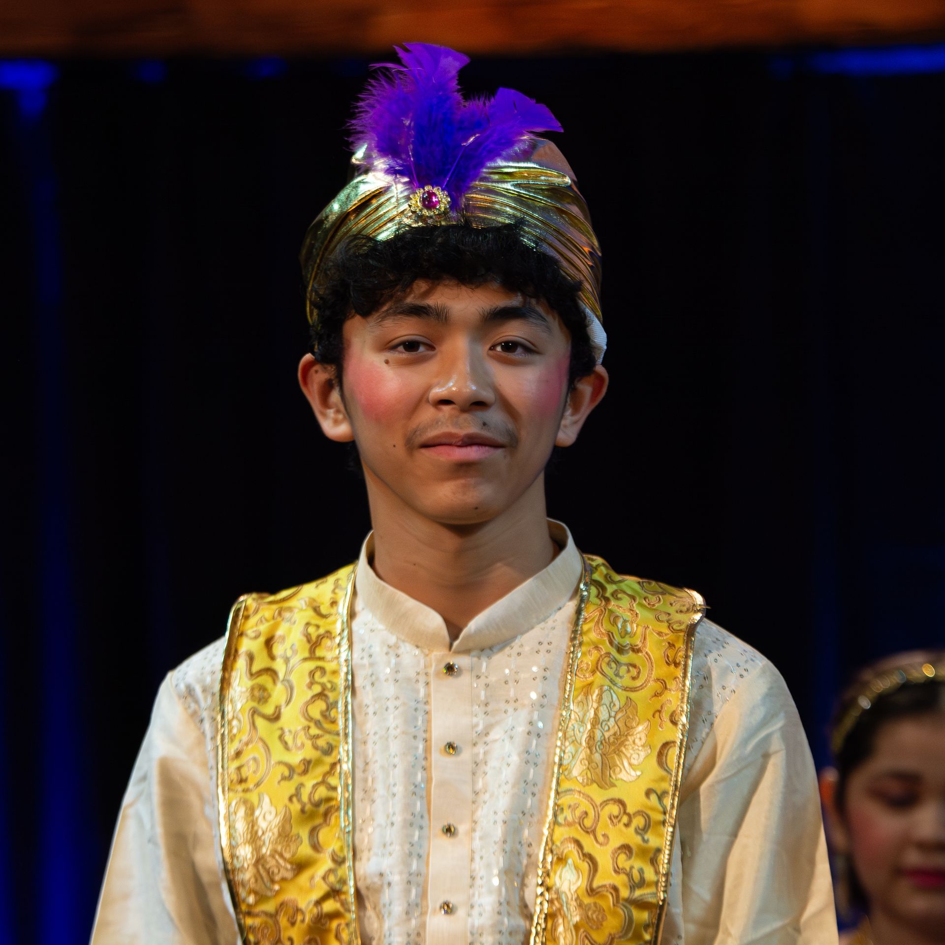 A young man in a costume with a purple feather on his head