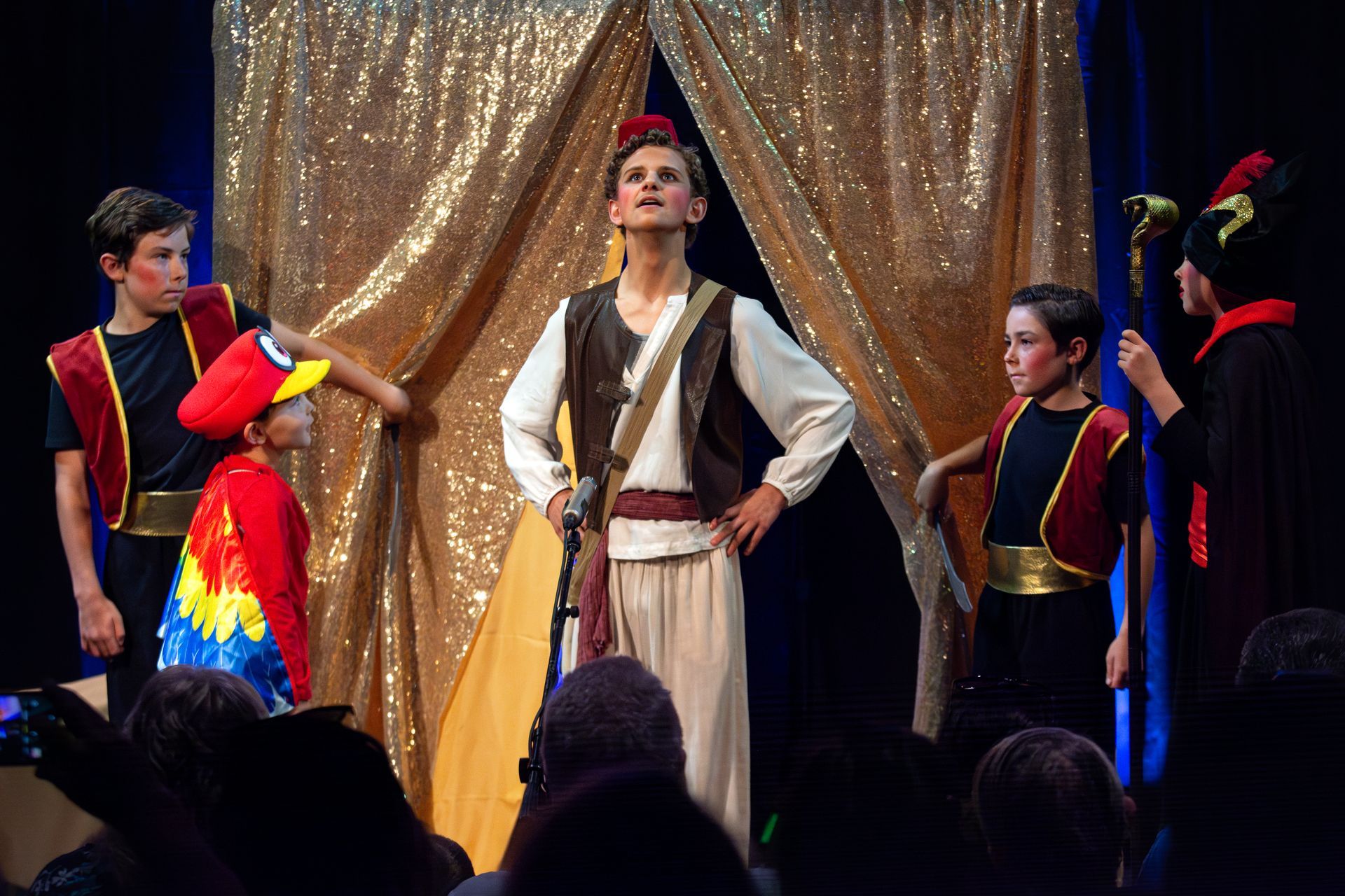 A group of children are standing on a stage in costume.