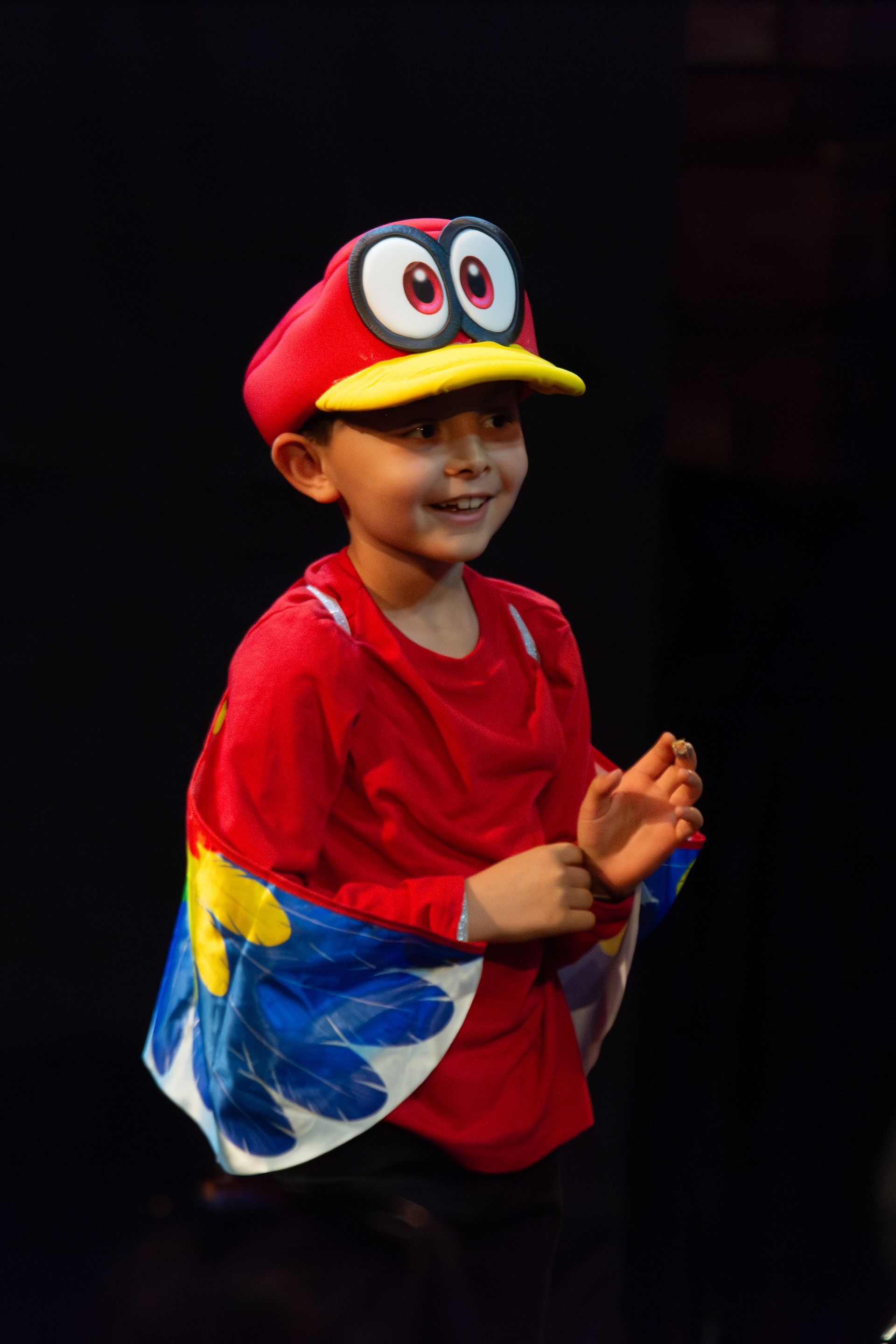 A young boy is wearing a red hat and a cape.