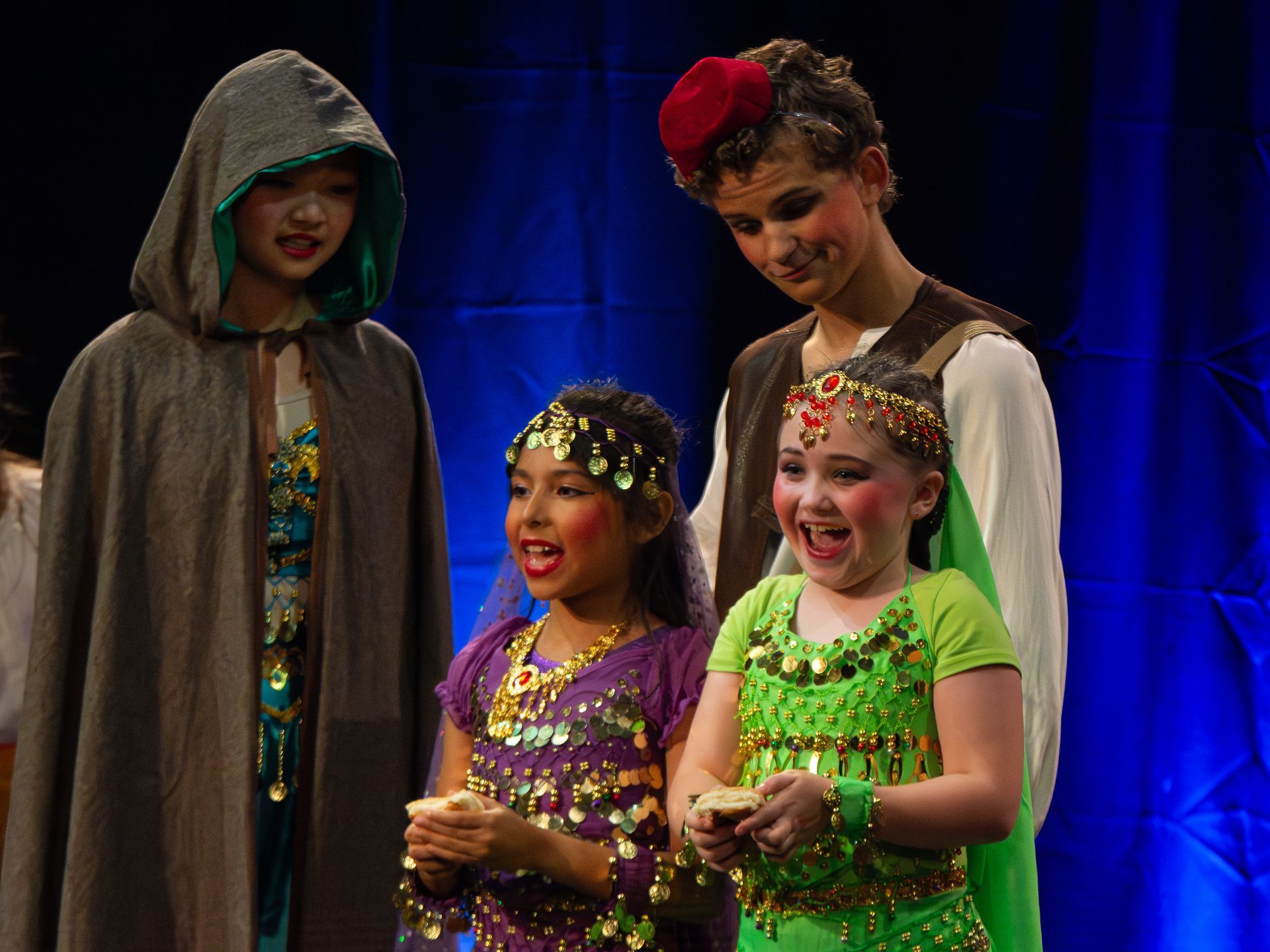 A group of children dressed in costumes are standing next to each other on a stage.