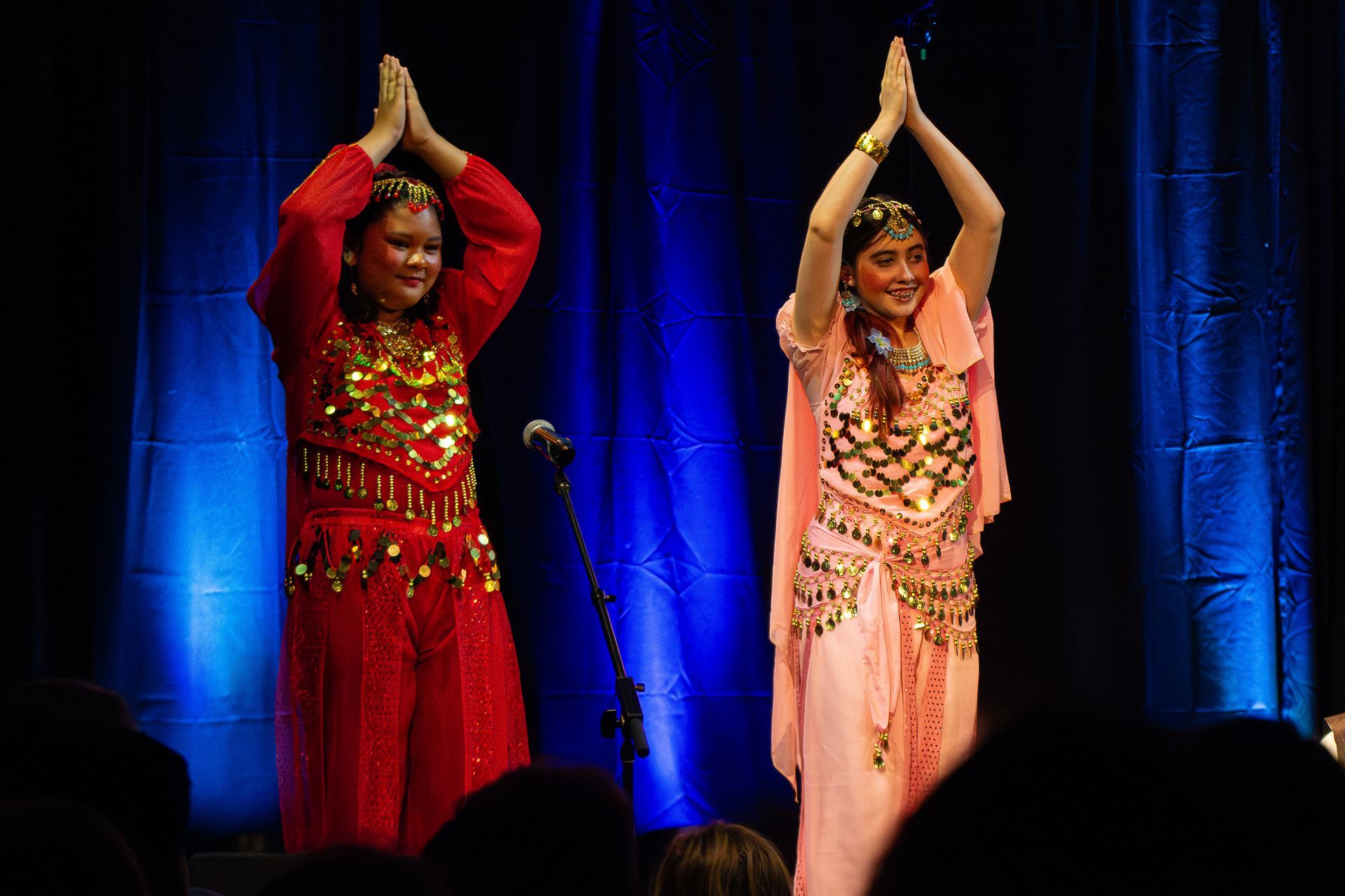 Two women are dancing on a stage with their hands in the air.