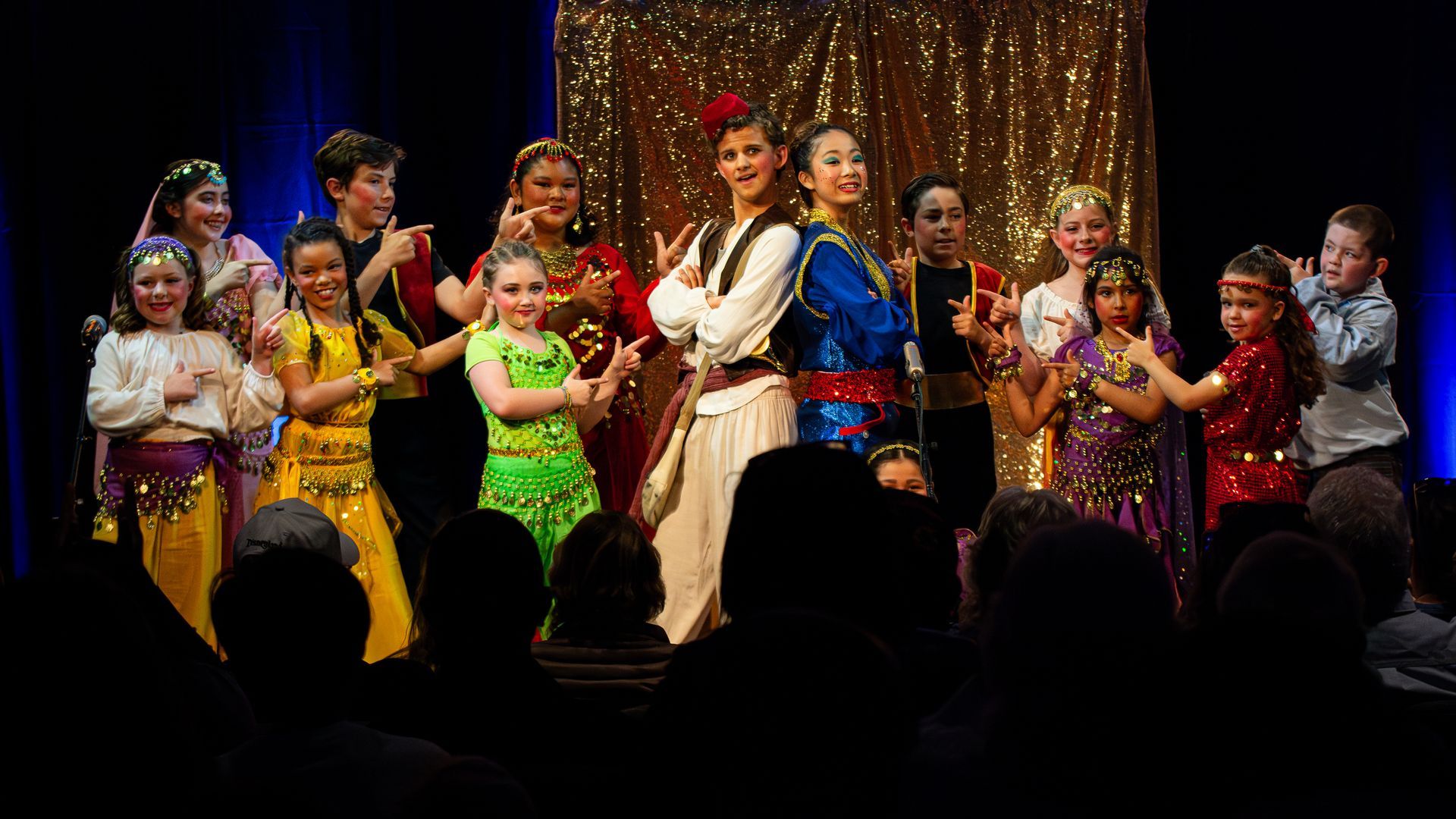 A group of children are dancing on a stage in front of a crowd.