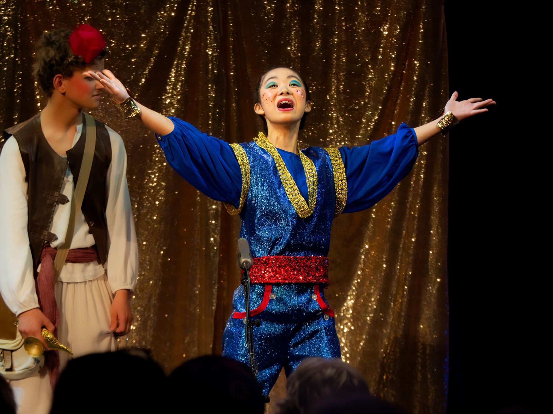 A woman singing into a microphone with her arms outstretched