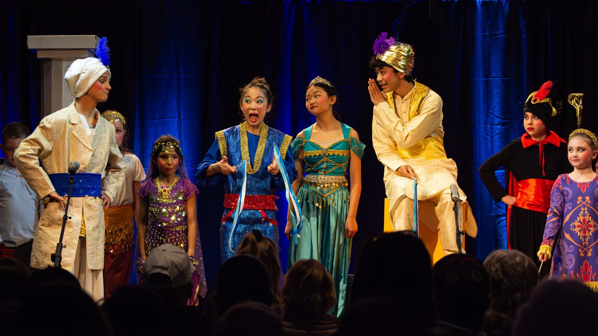 A group of people in costumes are standing on a stage in front of a crowd.