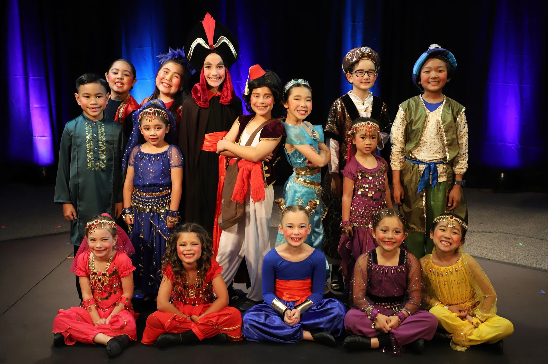 A group of children dressed in costumes are posing for a picture on a stage.