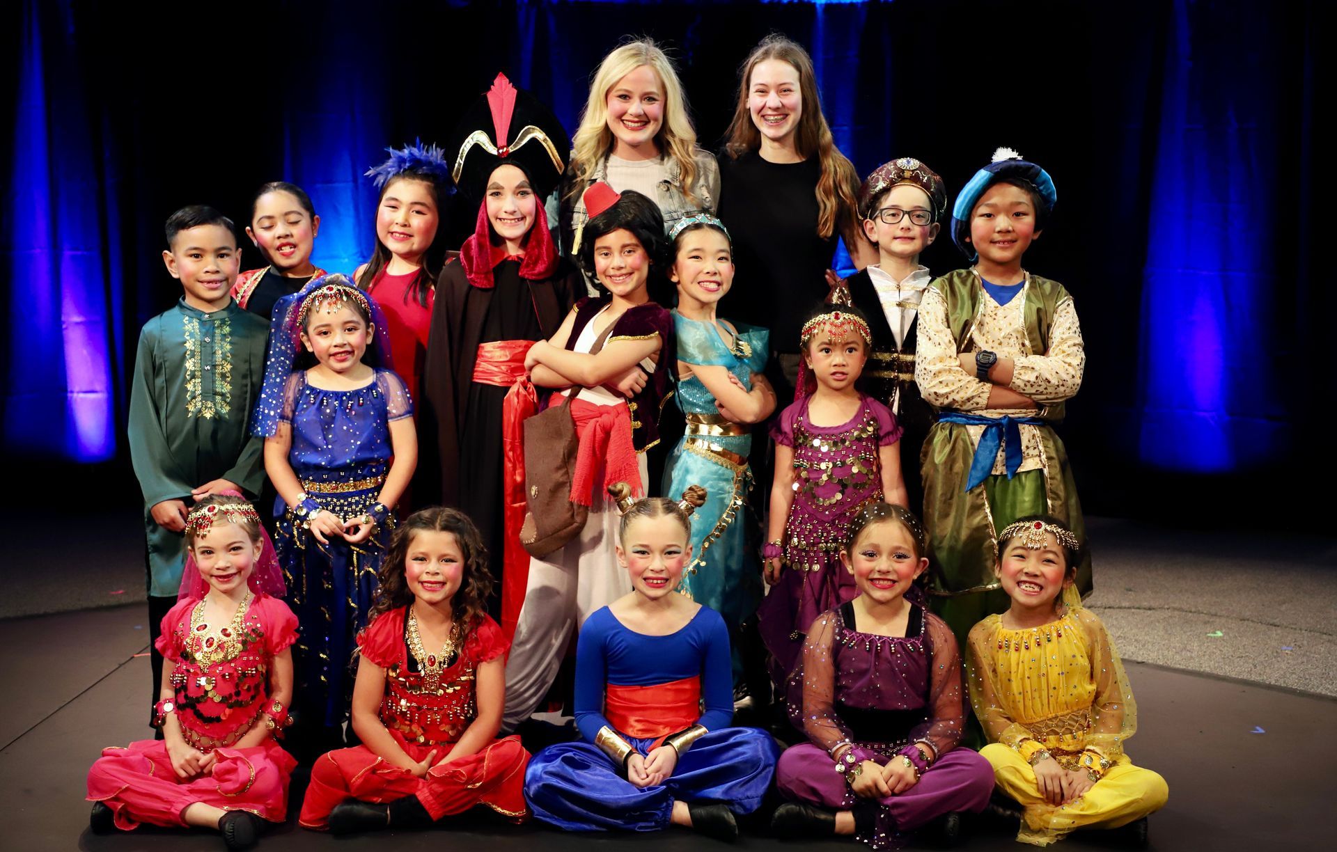A group of children dressed in costumes are posing for a picture on a stage.