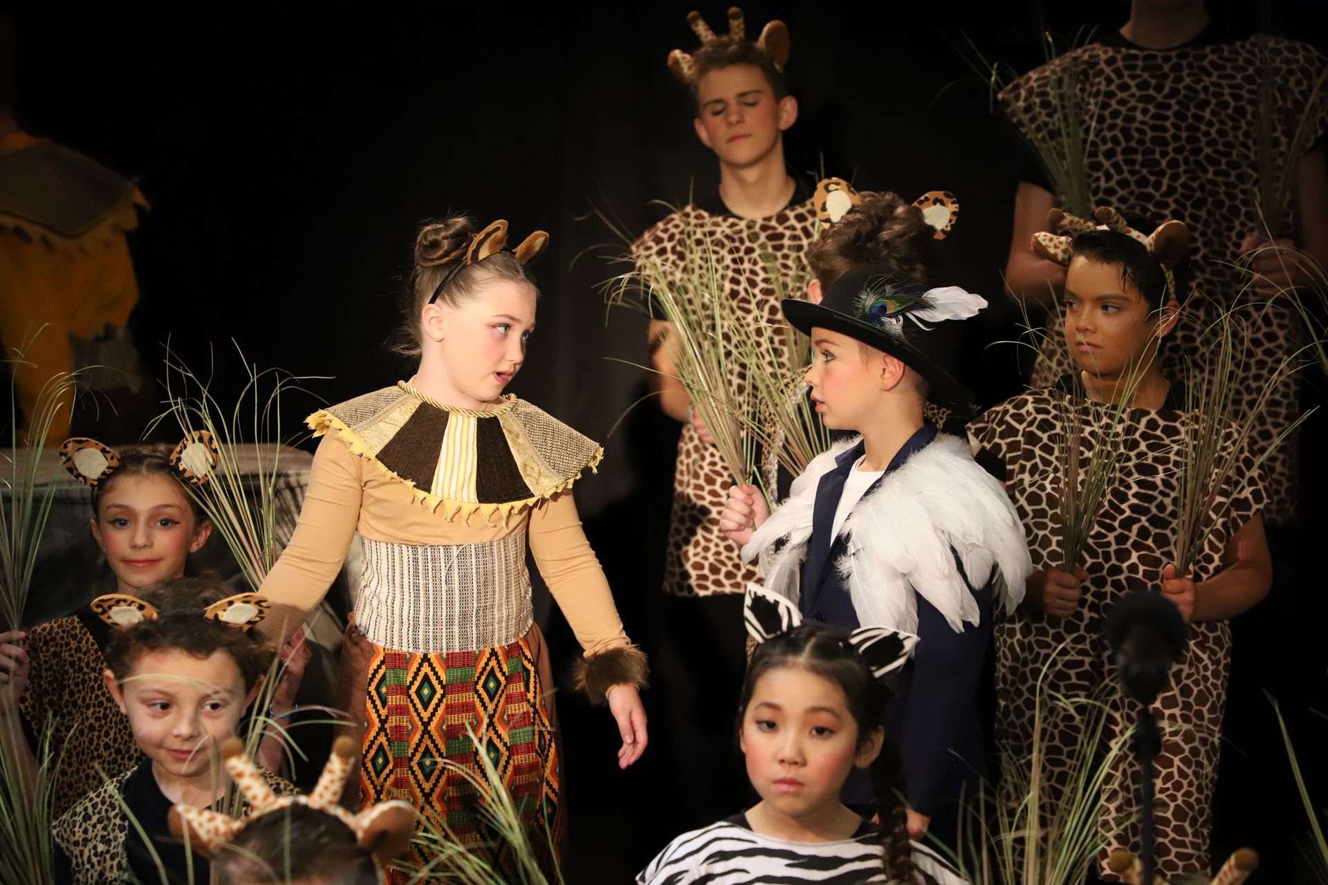 A group of children dressed in animal costumes are standing on a stage.