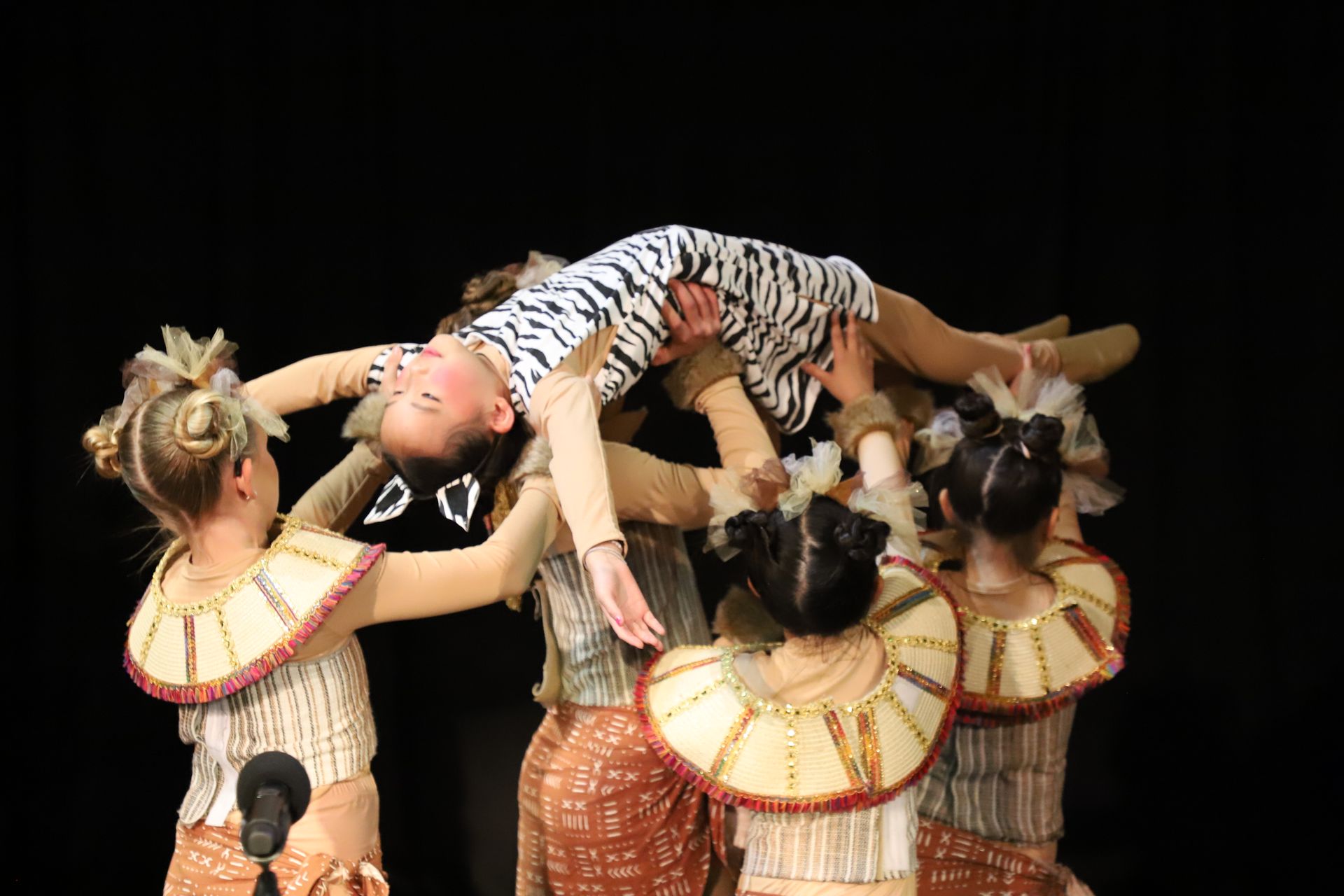 A group of young girls are performing a dance on a stage.